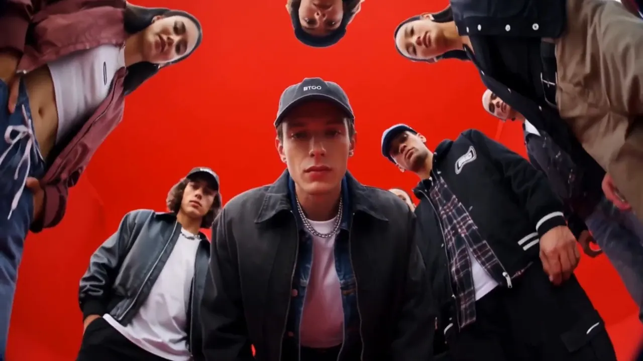 A group in streetwear looking down at the camera against a red background
